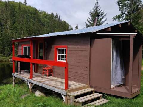 Vue extérieure du chalet Le Panoramique avec sa galerie aménagée au bord de l'eau.