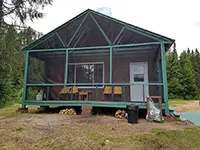 Front view of cabin 12 with its screened-in porch and outdoor chairs.