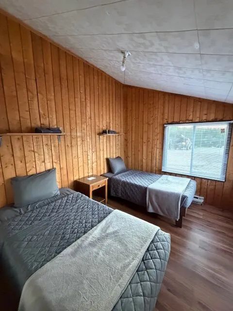 This cabin bedroom features two single beds with wood-paneled walls.