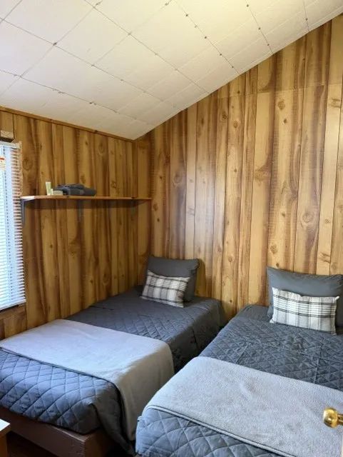 This bedroom in chalet 6 is equipped with two single beds featuring gray bedding.
