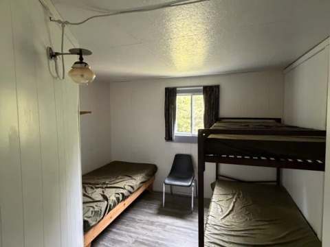 This bedroom in cabin 3 features a single bed and a bunk bed.