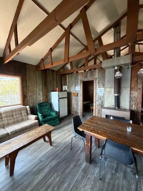 The cabin interior features a living area with a dining space and a wood stove.