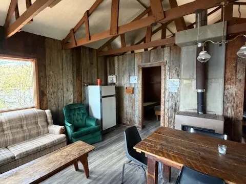 The cabin interior features a living area with a dining space and a wood stove.