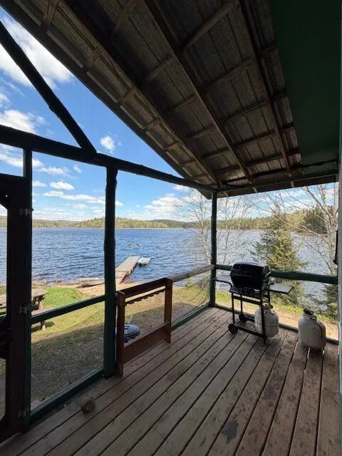 View of the lake and dock from the covered porch equipped with a barbecue at cottage 7.