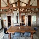 The dining room of chalet 7 features a large wooden table and a central stove.