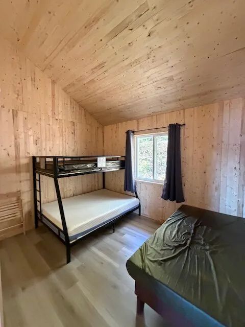 This bedroom in chalet 8 is equipped with a bunk bed and a single bed.
