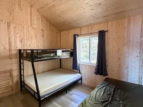 This bedroom in chalet 8 is equipped with a bunk bed and a single bed.