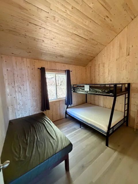 This cabin bedroom features one single bed and one bunk bed.