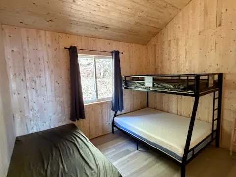 This cabin bedroom features one single bed and one bunk bed.