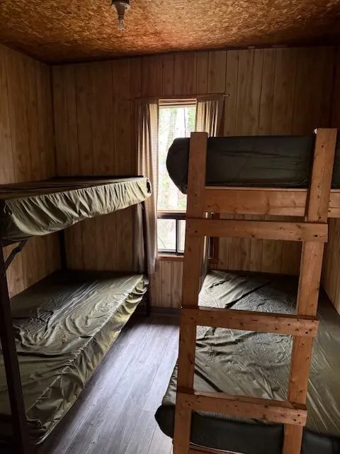 This cottage bedroom includes two wooden bunk beds with bedding.