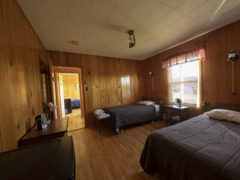 This inn bedroom features two single beds and wood paneled walls.