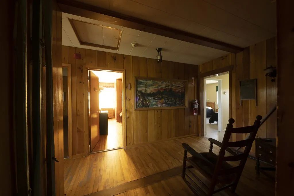 A wooden interior hallway with a rocking chair providing access to the various rooms.