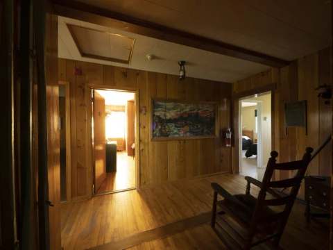 A wooden interior hallway with a rocking chair providing access to the various rooms.