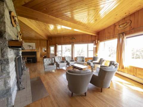 The lodge living room features a stone fireplace and comfortable armchairs near the windows.