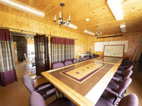 A meeting room featuring a large wooden table inside the lodge.
