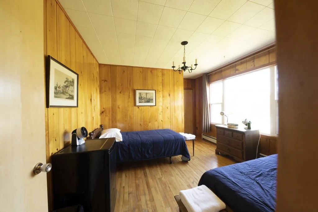 This room at Auberge 24 arpents is equipped with two single beds and wood paneling.
