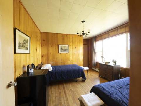 This room at Auberge 24 arpents is equipped with two single beds and wood paneling.