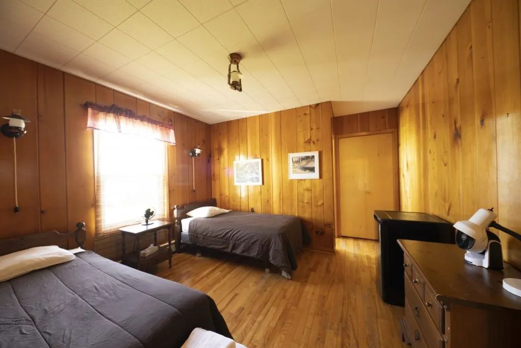 This room at Auberge 24 arpents is equipped with two single beds and wooden furniture.