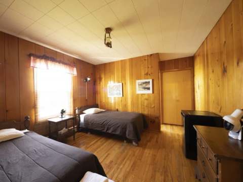 This room at Auberge 24 arpents is equipped with two single beds and wooden furniture.