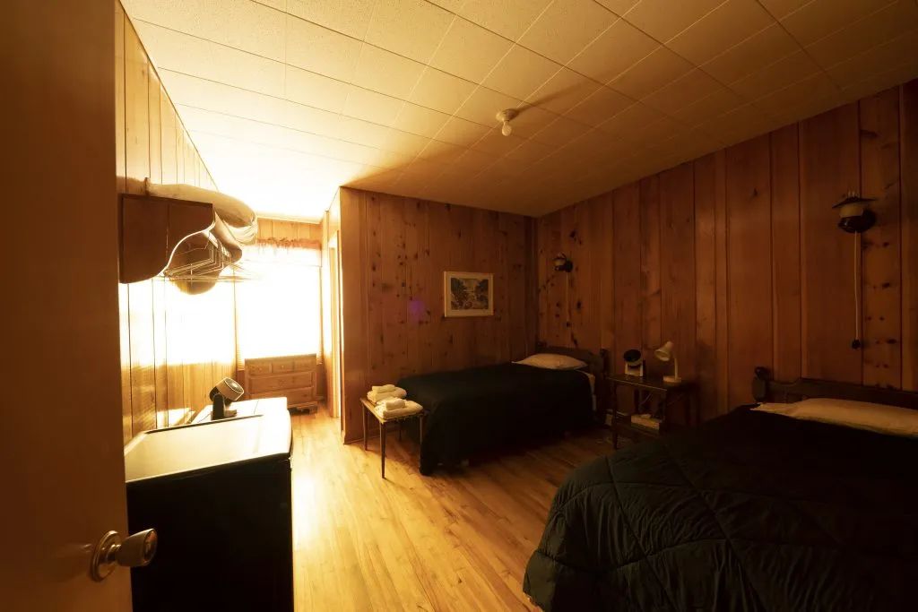 This inn room is equipped with two beds and wood paneling on the walls.