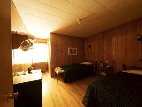 This inn room is equipped with two beds and wood paneling on the walls.