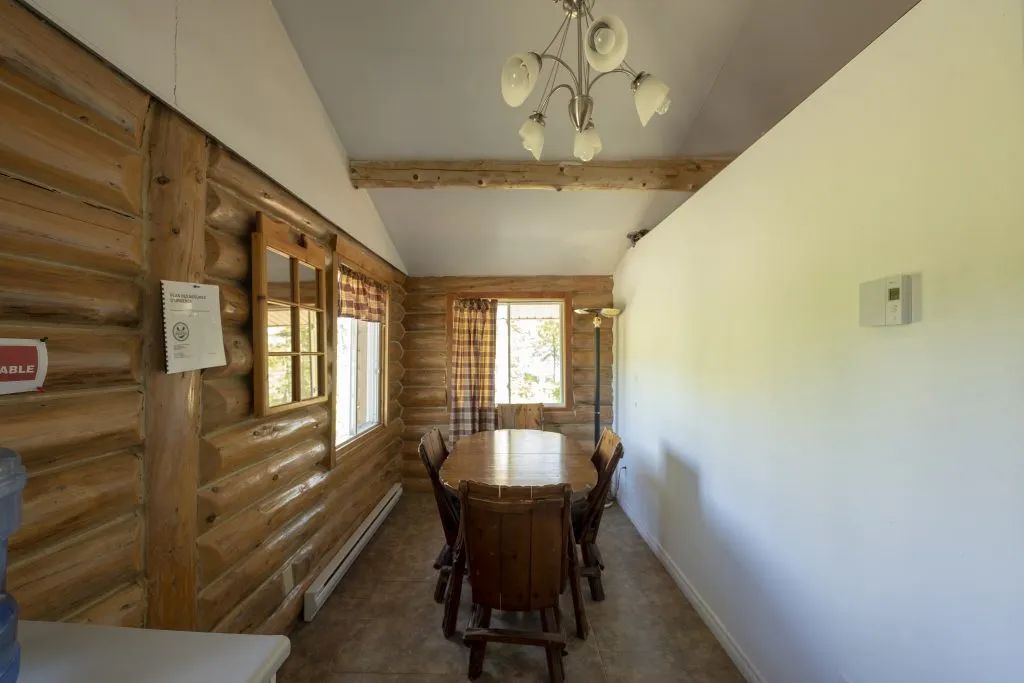 The cottage dining room features a wooden table and log walls.