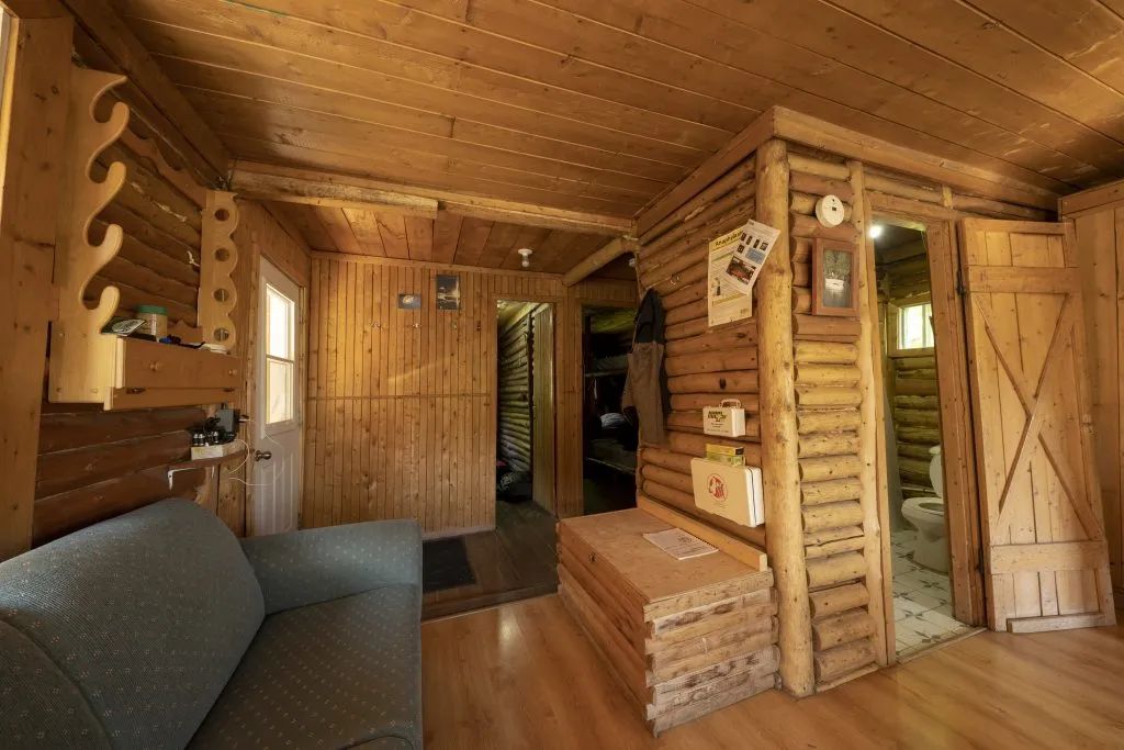 The rustic and cozy interior of this cabin features a seating area and access to the bedrooms.