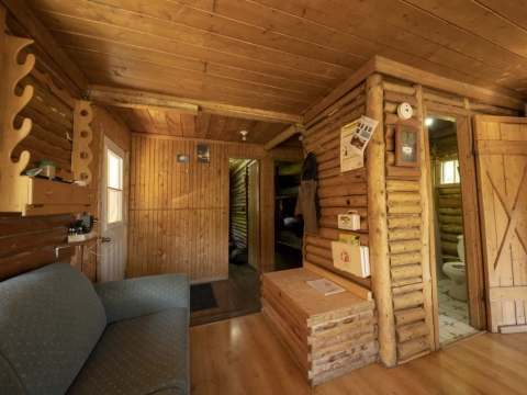 The rustic and cozy interior of this cabin features a seating area and access to the bedrooms.