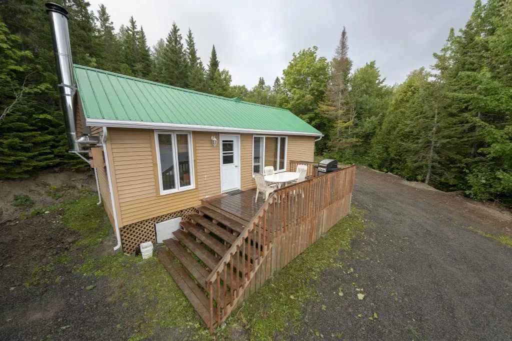 Exterior view of the cabin featuring a deck, patio furniture, and a barbecue.