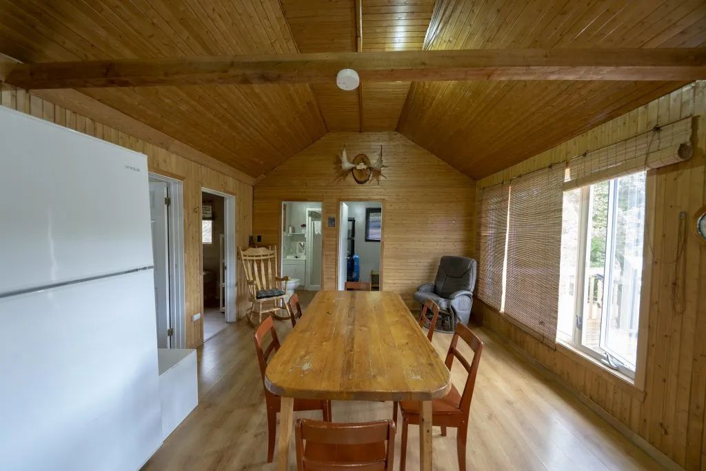 The cottage dining room features a wooden table and a view of the outdoors.