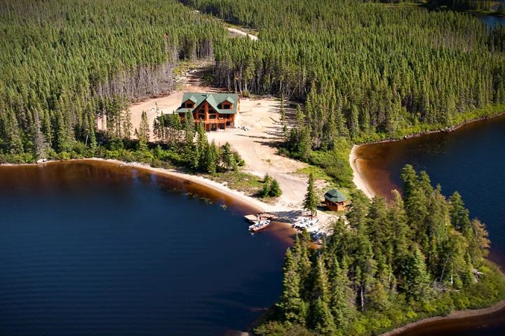 Aerial view of the lodge located by the lake and surrounded by the forest.