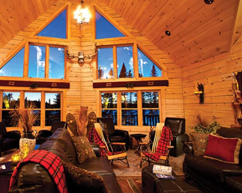 The lodge's cozy living room offers a stunning view of the surrounding nature.