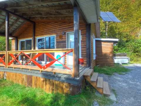 Le chalet Mario dispose d'une galerie couverte avec une rampe en bois à l'orée de la forêt.