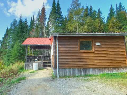 Le Chalet Noir offre une vue paisible avec sa galerie couverte située en bordure de la forêt.