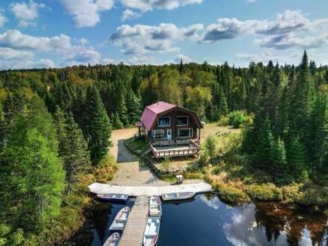 Vue aérienne du chalet Petit bois franc avec son quai et ses embarcations au bord de l'eau.