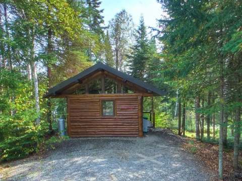 Vue latérale du mini chalet en bois situé en pleine forêt.