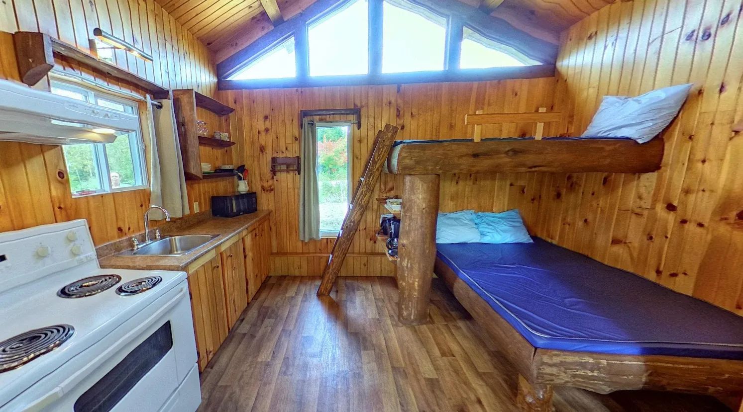 The interior of the Oasis mini cabin features a kitchen area and wooden bunk beds.