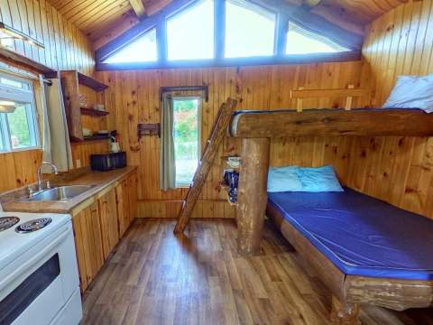 L'intérieur du mini chalet Oasis dispose d'un espace cuisine et de lits superposés en bois.