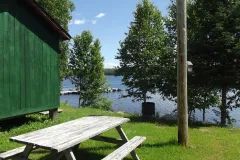 Une table de pique-nique est installée à l'extérieur du chalet, offrant une vue sur le lac.
