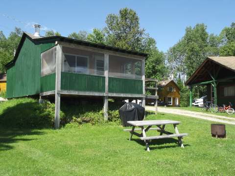 Chalet 1 features a screened porch, a picnic table, and an outdoor barbecue.