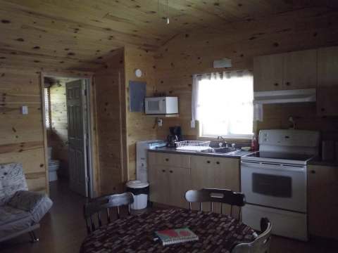 The equipped kitchen and dining area of cottage 1 offer a warm, all-wood space.