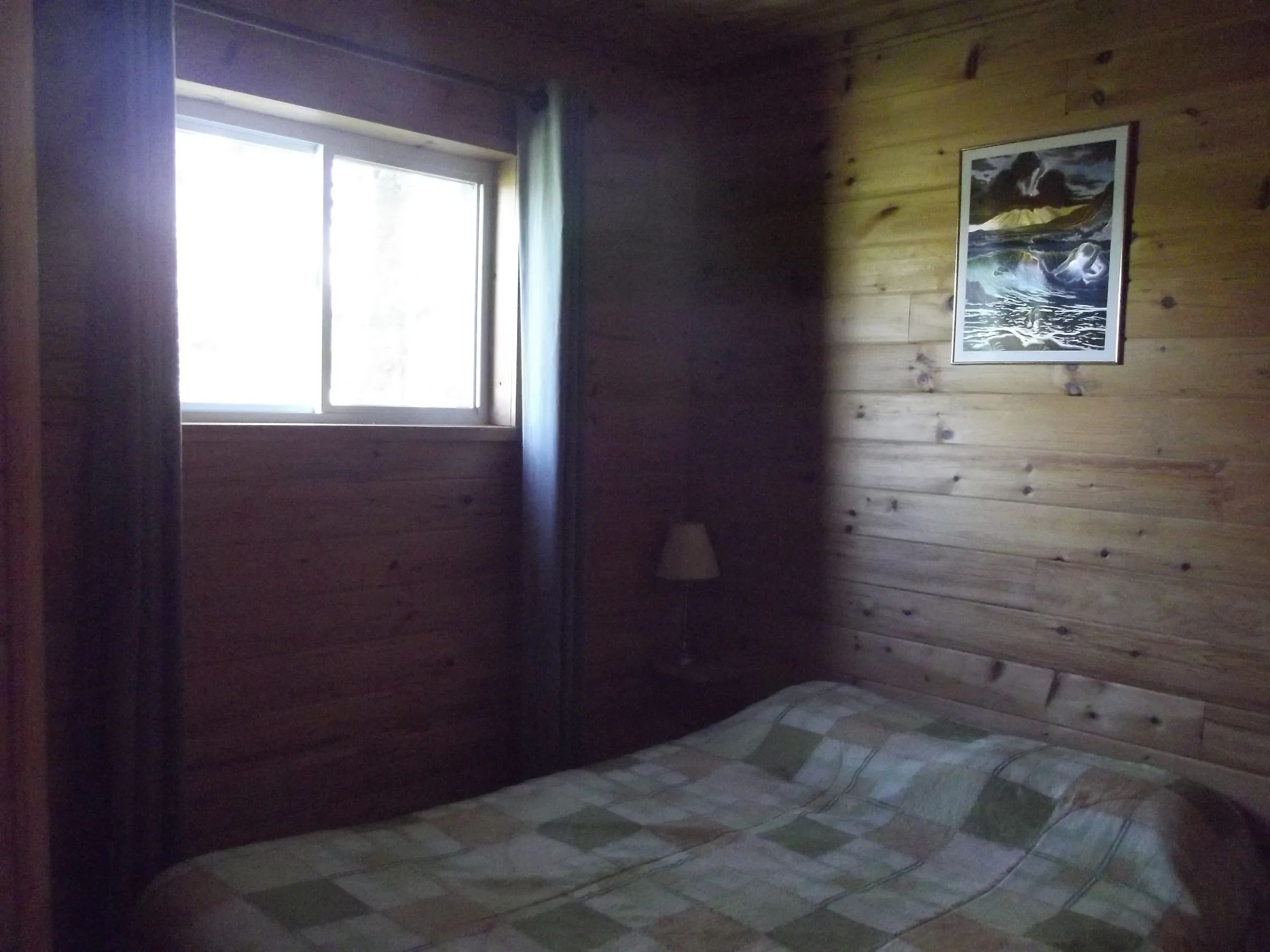 A bedroom with a bed and wood-paneled walls in cottage 10.