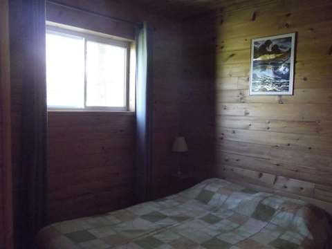 A bedroom with a bed and wood-paneled walls in cottage 10.