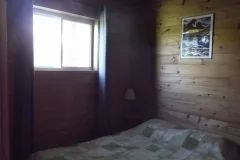 A comfortable bedroom with a bed and wood-paneled walls inside the cottage.