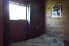 A comfortable bedroom with a bed and wood-paneled walls inside the cottage.