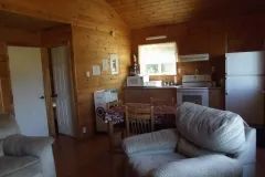 The chalet's open living area includes a seating area, a dining table, and an equipped kitchen.