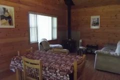 The living room and dining area of cabin 10 are furnished with a table, armchairs, and a stove.