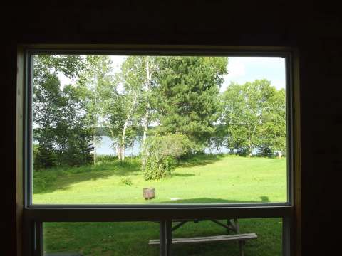 View of the outdoor grounds and the water from inside the cabin.