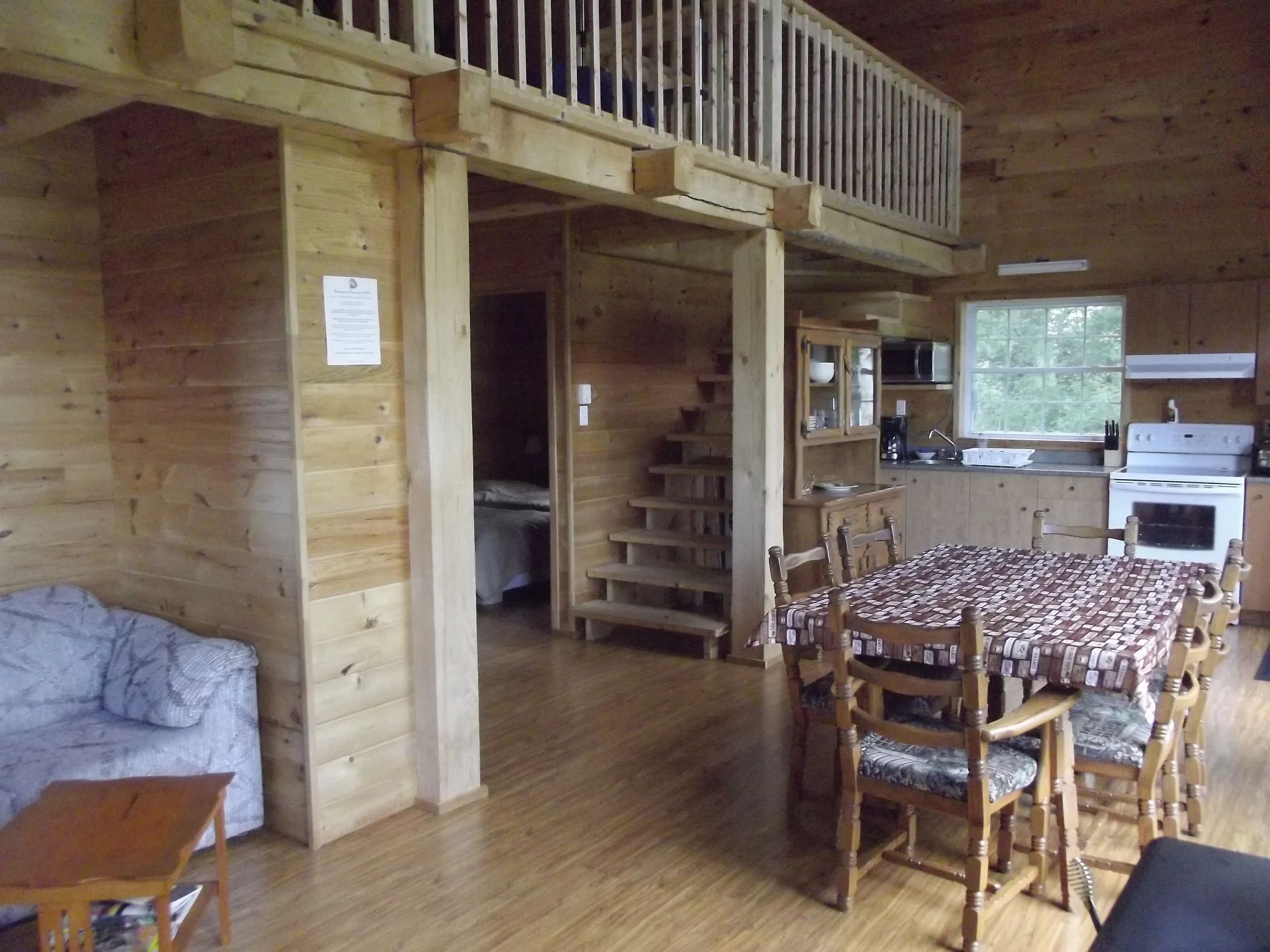 Overview of the main living area featuring a kitchen, dining area, and a wooden mezzanine.