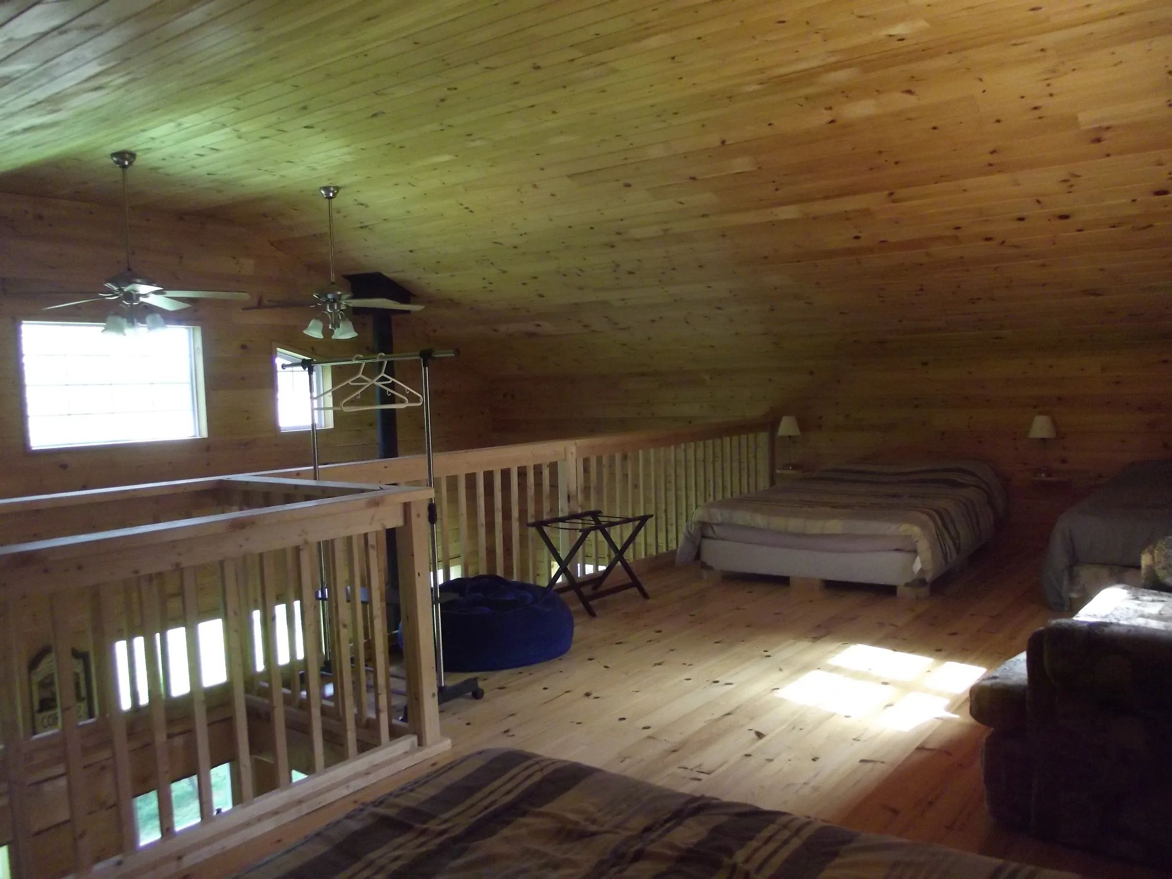 The mezzanine of cabin 11 features several beds and natural wood flooring.